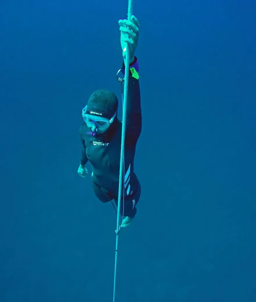 Sofia freediving along a rope in deep blue water